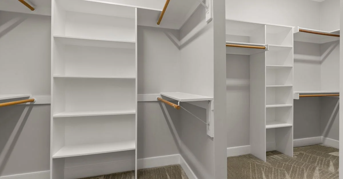Vestidor moderno, luminoso y espacioso, con estantes blancos y barandillas de madera.